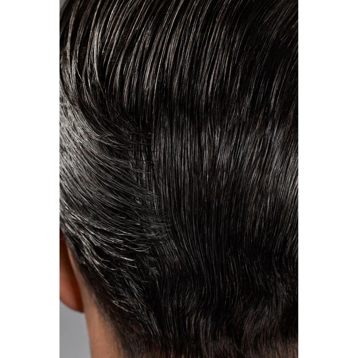 Close-up of neatly styled slick back black hair showing texture and shine.