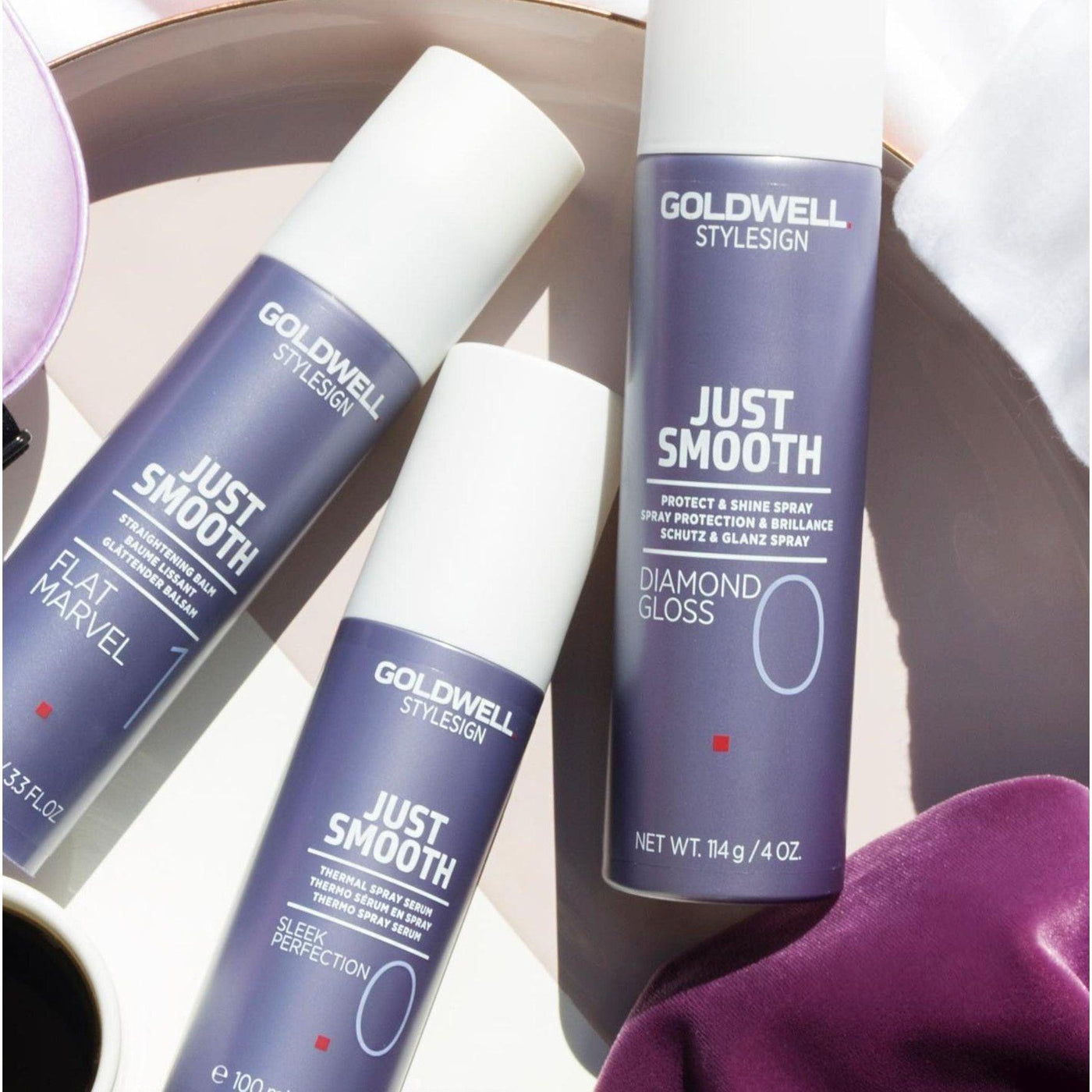 Goldwell Just Smooth hair care products, including Sleek Perfection and Diamond Gloss, arranged on a stylish background.