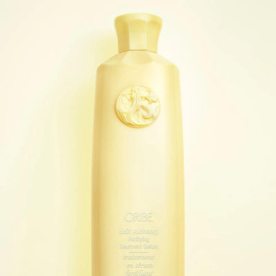 Oribe Hair Alchemy Fortifying Treatment Serum bottle featuring a sleek design and luxurious branding on a light background.