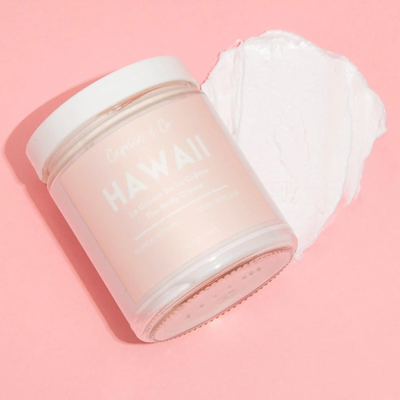 Hawaii body cream in a glass jar with creamy texture on pink background, hydrating with natural ingredients.