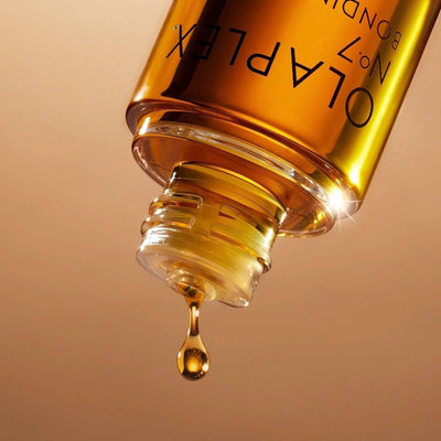 Close-up of Olaplex No.7 Styling Oil bottle, showcasing the golden oil dripping from the top for hair protection and shine.