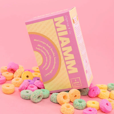 Miamm mini bath bombs packaging surrounded by colorful bath bomb rings on a pink background.