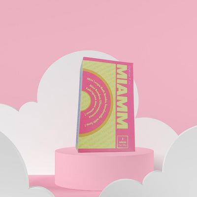 Miamm mini bath bombs packaging displayed on a pastel pink background with clouds, highlighting sweet citrus scent and skin benefits.