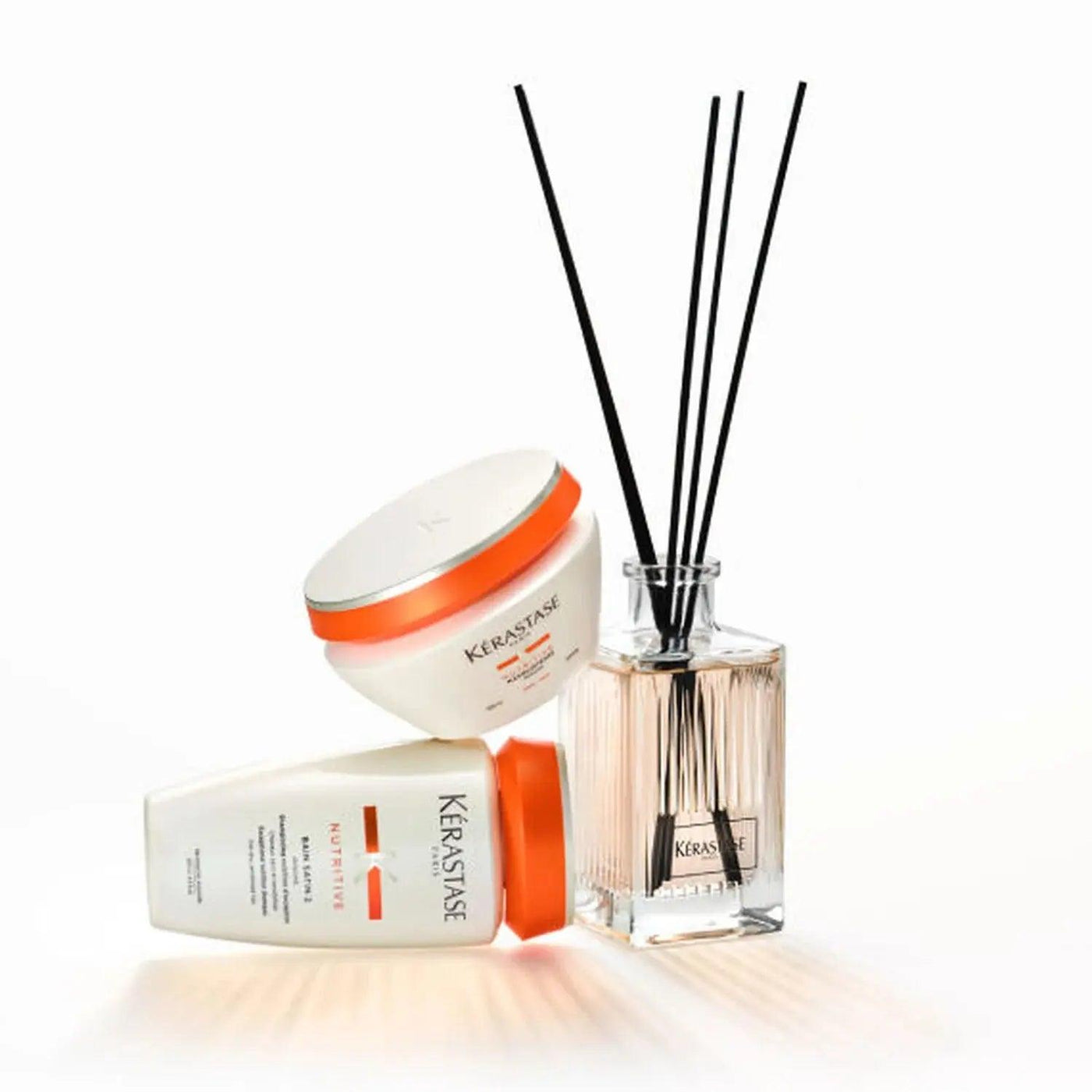Kérastase nutritive home fragrance diffuser with sticks and hair care products on a light background.