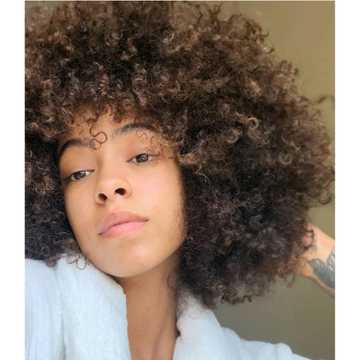 Woman with beautiful, voluminous curly hair showcasing healthy, moisturized curls.