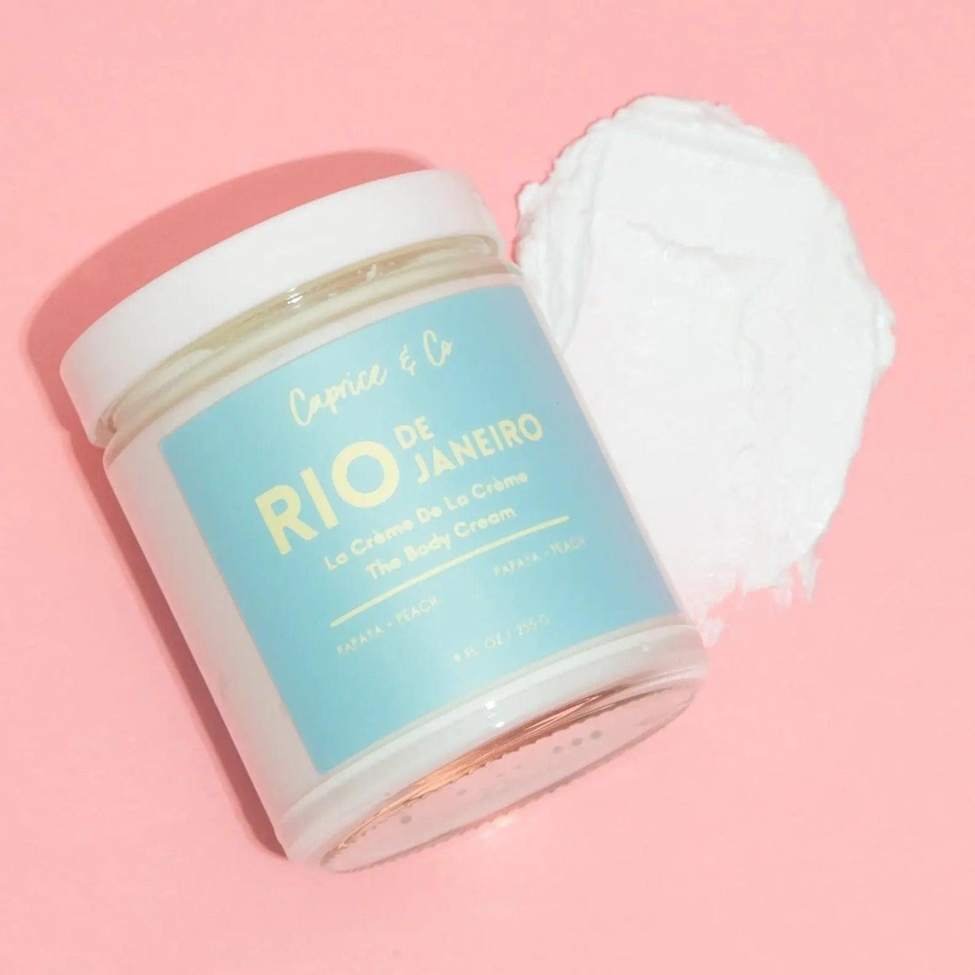 Rio de Janeiro body cream jar and creamy texture on a pink background, featuring natural ingredients for hydration.