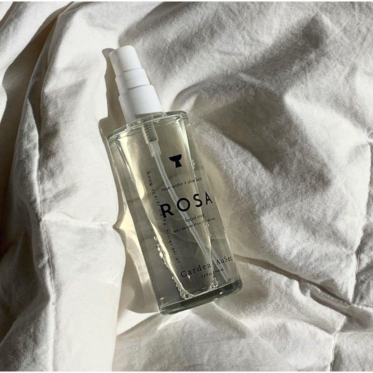 Rosa skincare product bottle on wrinkled white fabric in natural light.