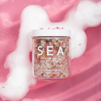 SEA mineral soak jar with pink bath water and foam background for luxury self-care and relaxation.