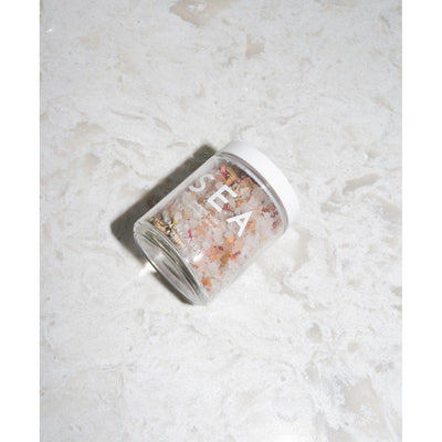 Glass jar of sea salt on marbled surface, labeled 'SEA'