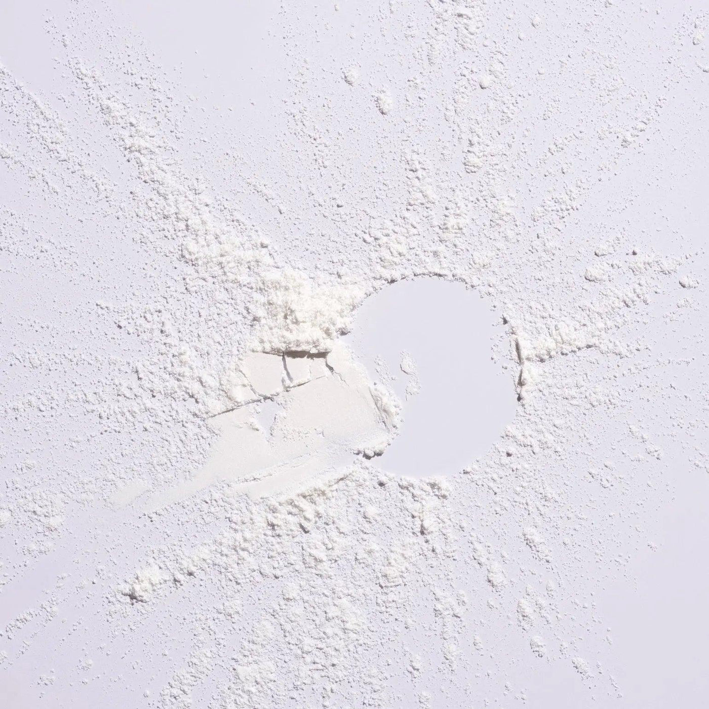 White powder scattered on a surface, representing Serene Scalp Oil Control Dry Shampoo Powder by Shu Uemura.