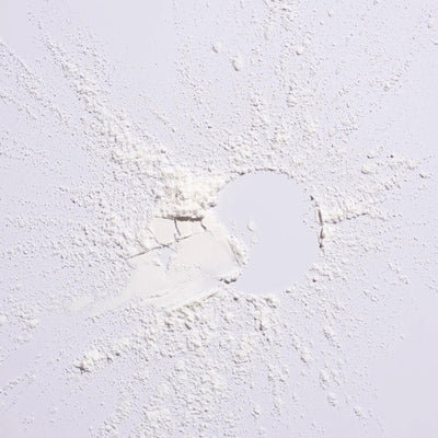 White powder scattered on a surface, representing Serene Scalp Oil Control Dry Shampoo Powder by Shu Uemura.