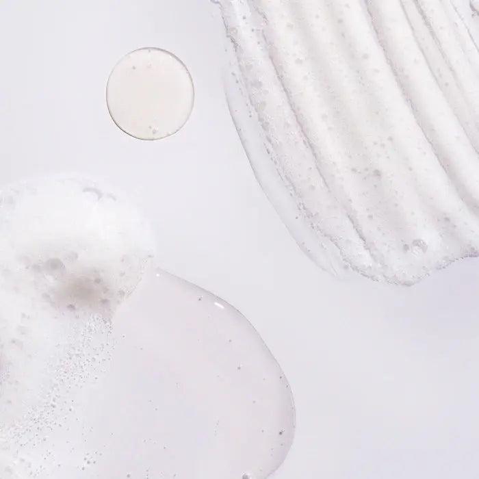 close-up of Oribe Serene Scalp Oil Control Shampoo texture, showcasing a foamy and creamy consistency on a light background