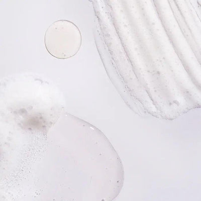 close-up of Oribe Serene Scalp Oil Control Shampoo texture, showcasing a foamy and creamy consistency on a light background