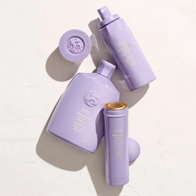 Oribe Serene Scalp Oil Control Shampoo and products in purple packaging on a textured surface.