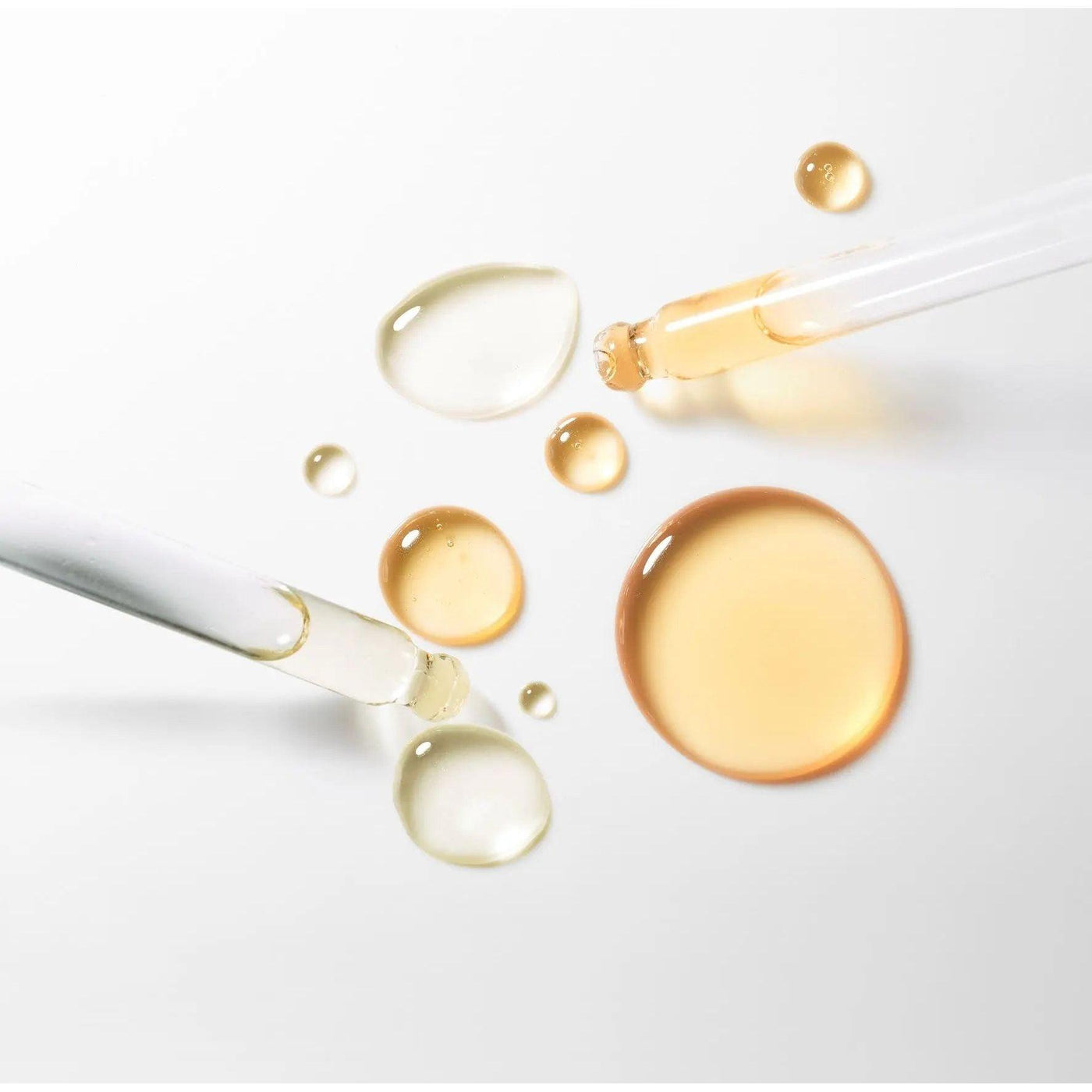 Drops of serum in various colors with pipettes, showcasing the luxurious texture of the Serum Absolut Firming Booster.