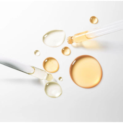 Drops of serum in various colors with pipettes, showcasing the luxurious texture of the Serum Absolut Firming Booster.