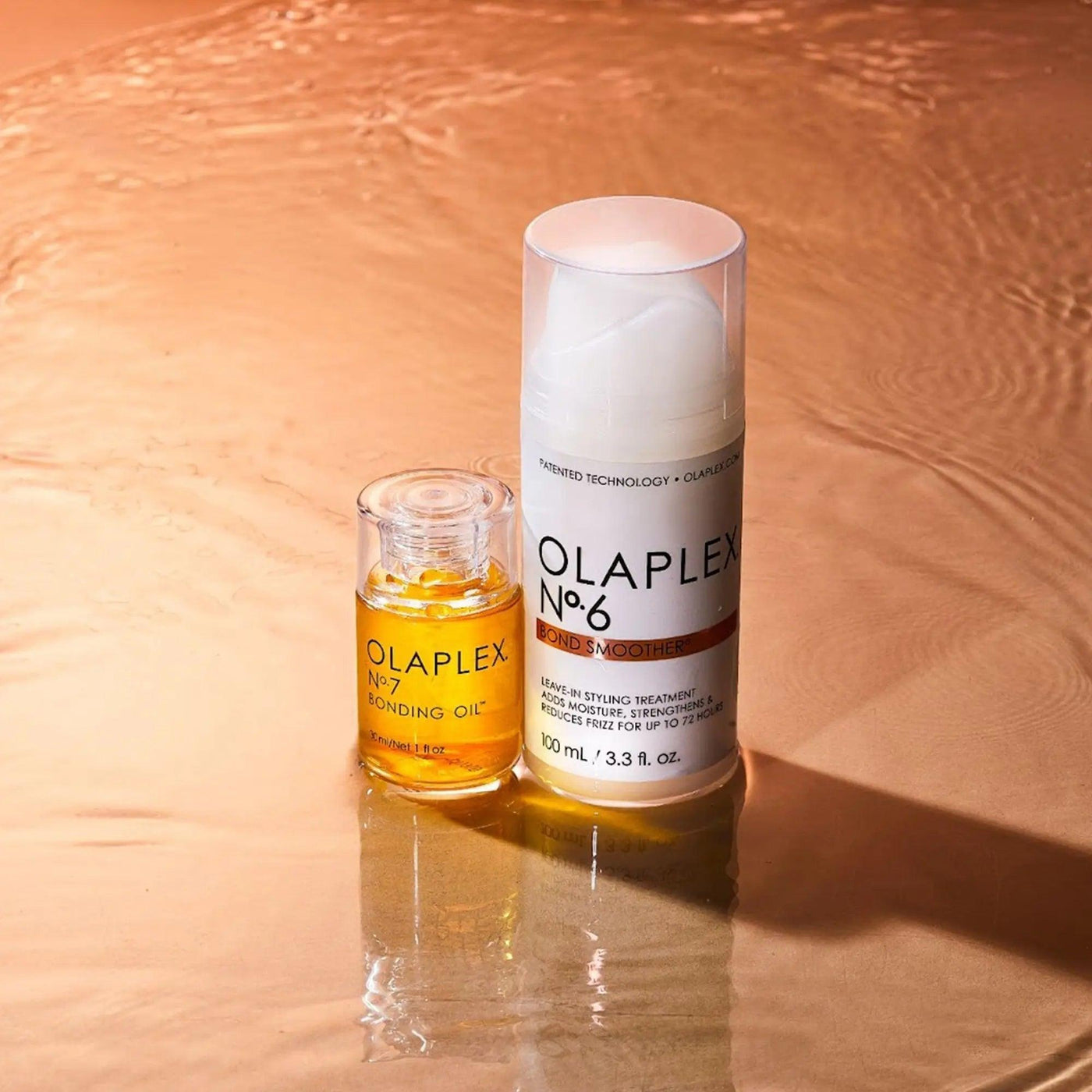 Olaplex Nº.6 Bond Smoother and Nº.7 Bonding Oil on a reflective surface, highlighting hair care products for shine and protection.