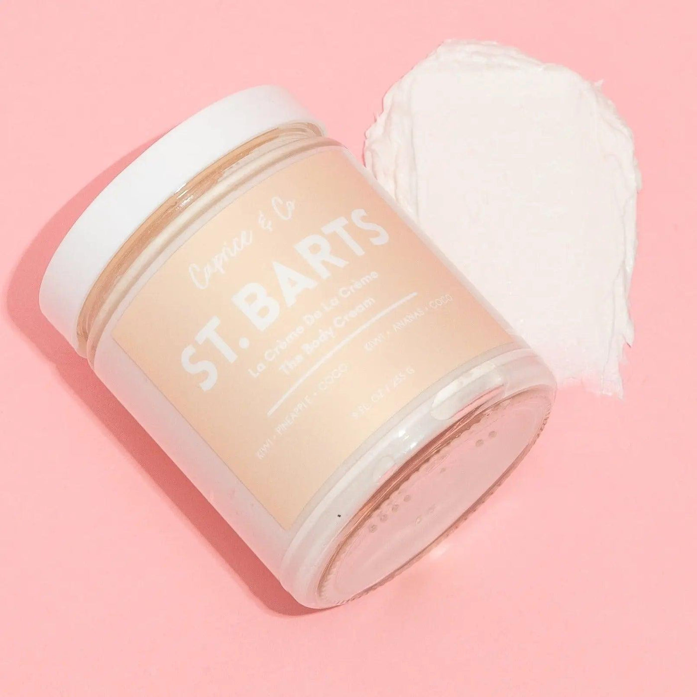 St-Barts body cream in a glass jar with a soft cream texture on a pink background, featuring kiwi, pineapple, and coconut scent.