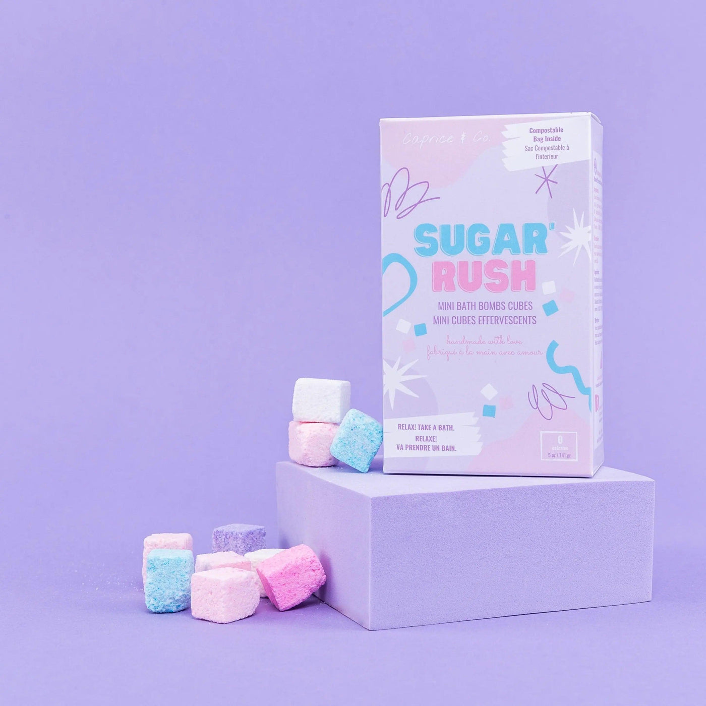 Sugar Rush mini bath bombs in pastel colors on a purple background with packaging, perfect for a relaxing bath experience.