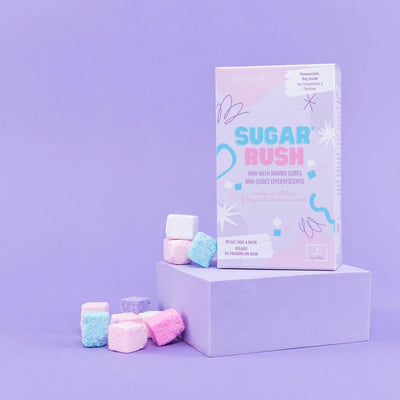 Sugar Rush mini bath bombs in pastel colors on a purple background with packaging, perfect for a relaxing bath experience.