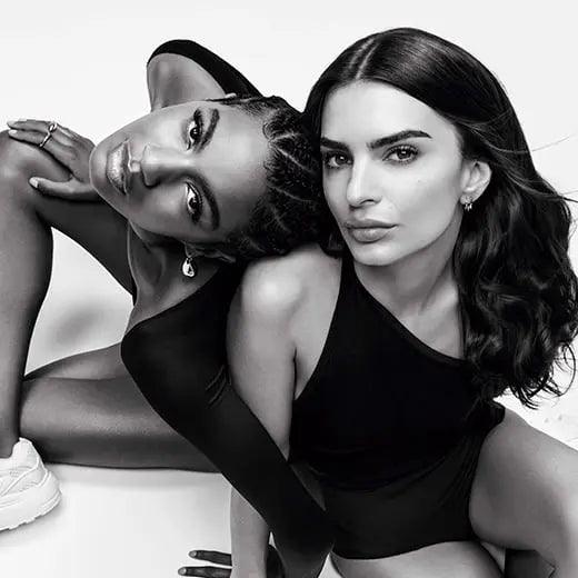 Two women posing in stylish black outfits, showcasing elegance and confidence in a striking black and white photo.