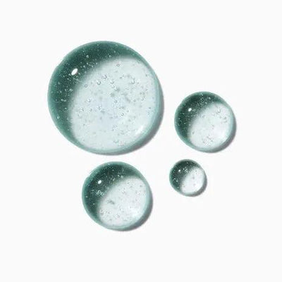 Close-up of green and clear serum droplets, showcasing a textured gel ideal for revitalizing hair overnight.
