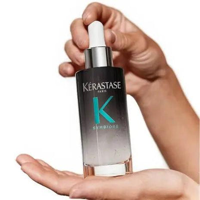 Kérastase Symbiose Sérum Nuit Intensif held in hand, designed for revitalizing damaged hair overnight.