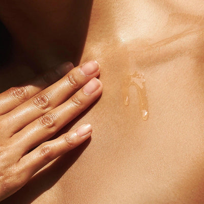Hand gently applying The Oil on glowing skin, showcasing its luxurious texture and nourishing benefits.