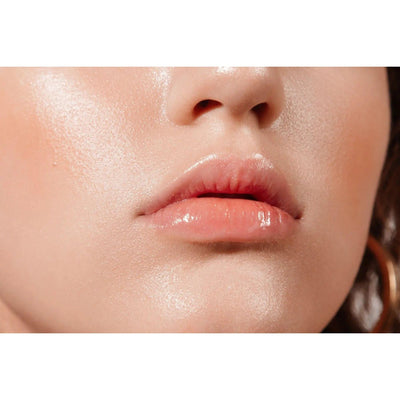 Close-up of woman's glossy lips and flawless skin showcasing natural beauty and skincare.