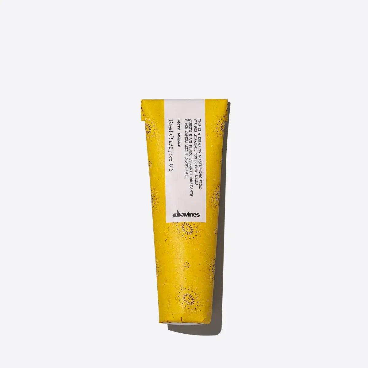 Yellow Davines beauty product tube with white label and floral pattern on plain background.