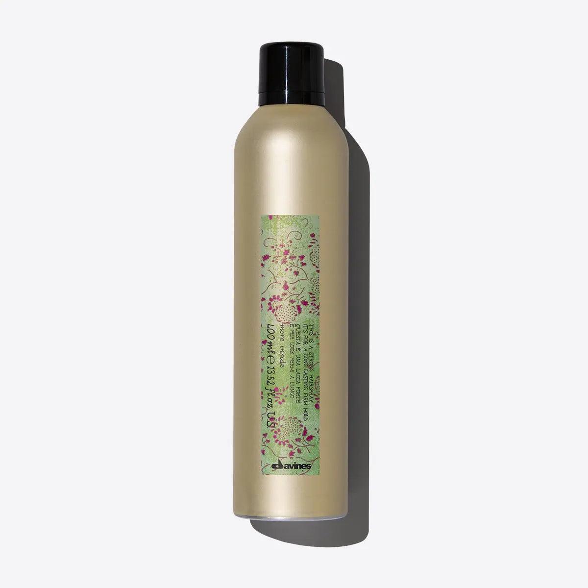 Premium hair care spray in golden bottle with floral label, green and pink colors, isolated on white background.