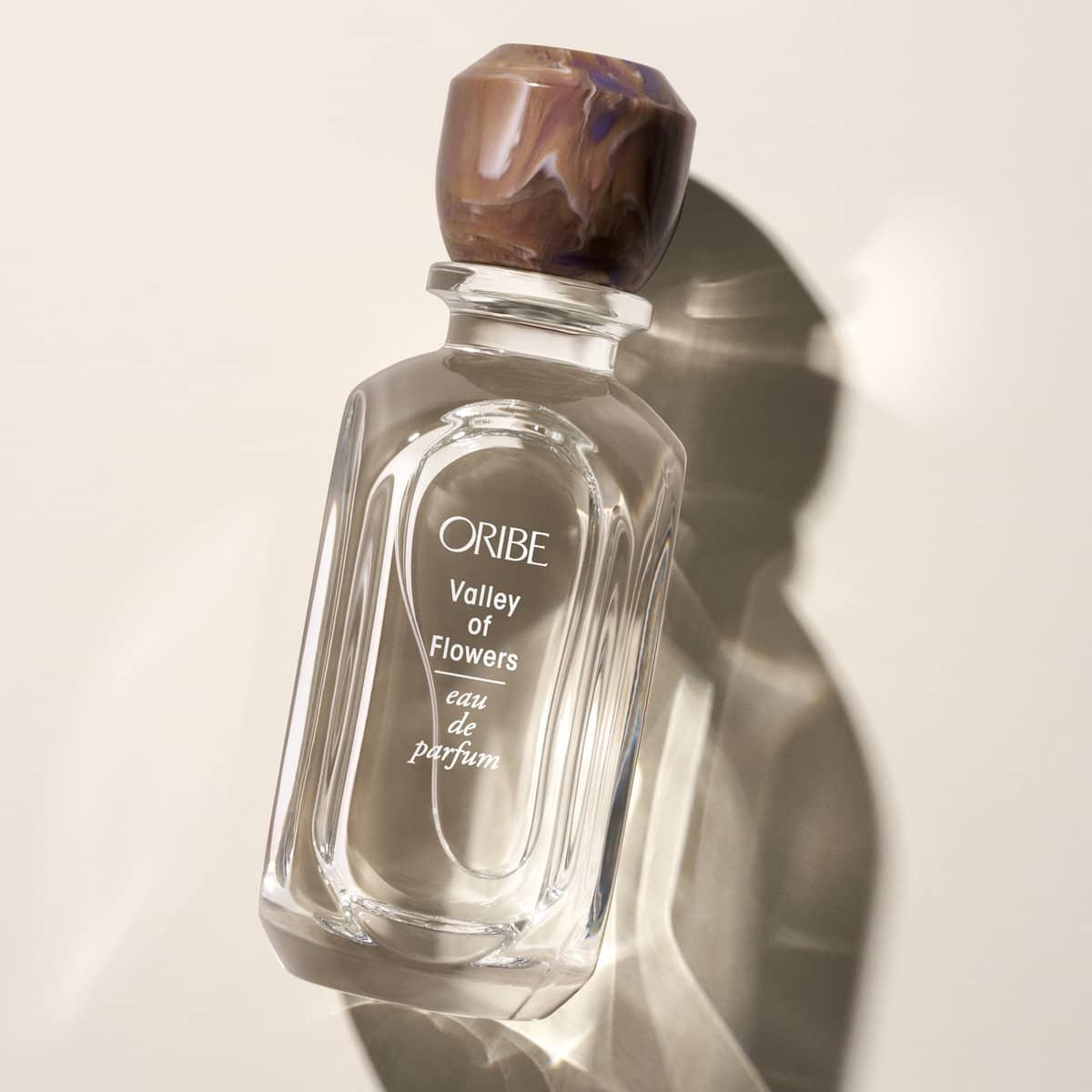 Luxury Oribe Valley of Flowers eau de parfum perfume bottle on a beige background.