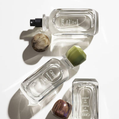 Oribe perfume bottles with decorative caps on white background, luxury fragrance collection, high-end designer perfume.