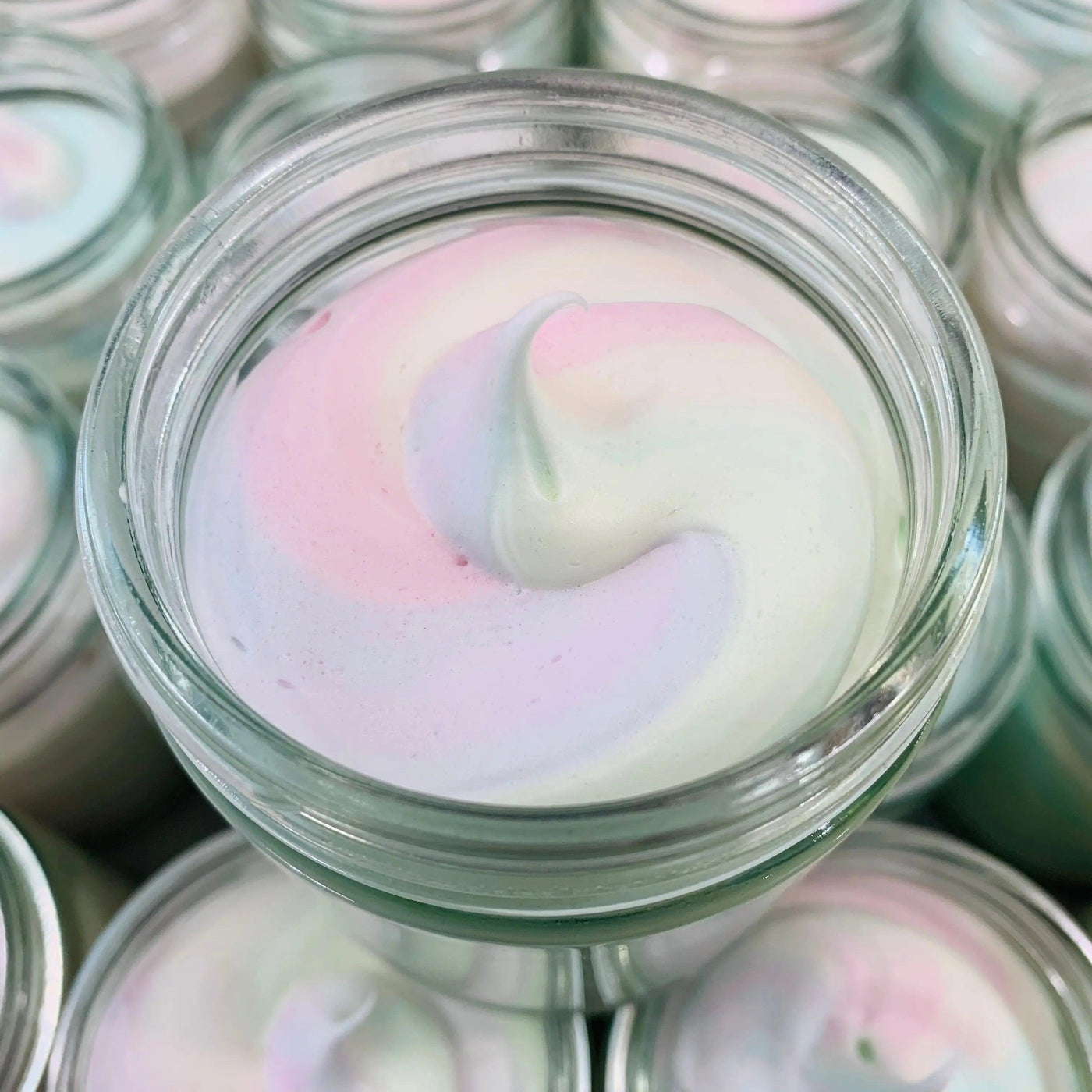 Close-up of natural whipped soap in a jar, featuring a fluffy swirl of pastel colors. Ideal for moisturizing and sensitive skin.